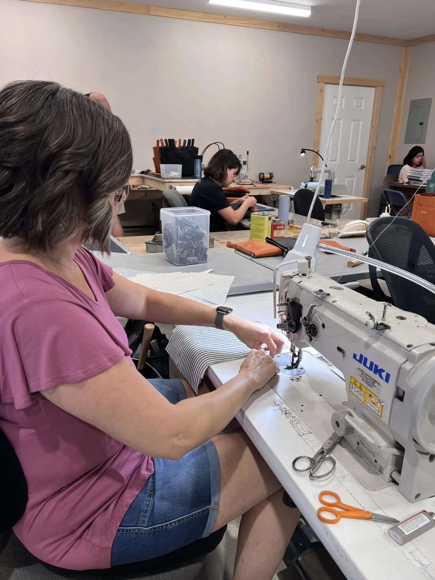A lady sewing a linen liner for a leather bag