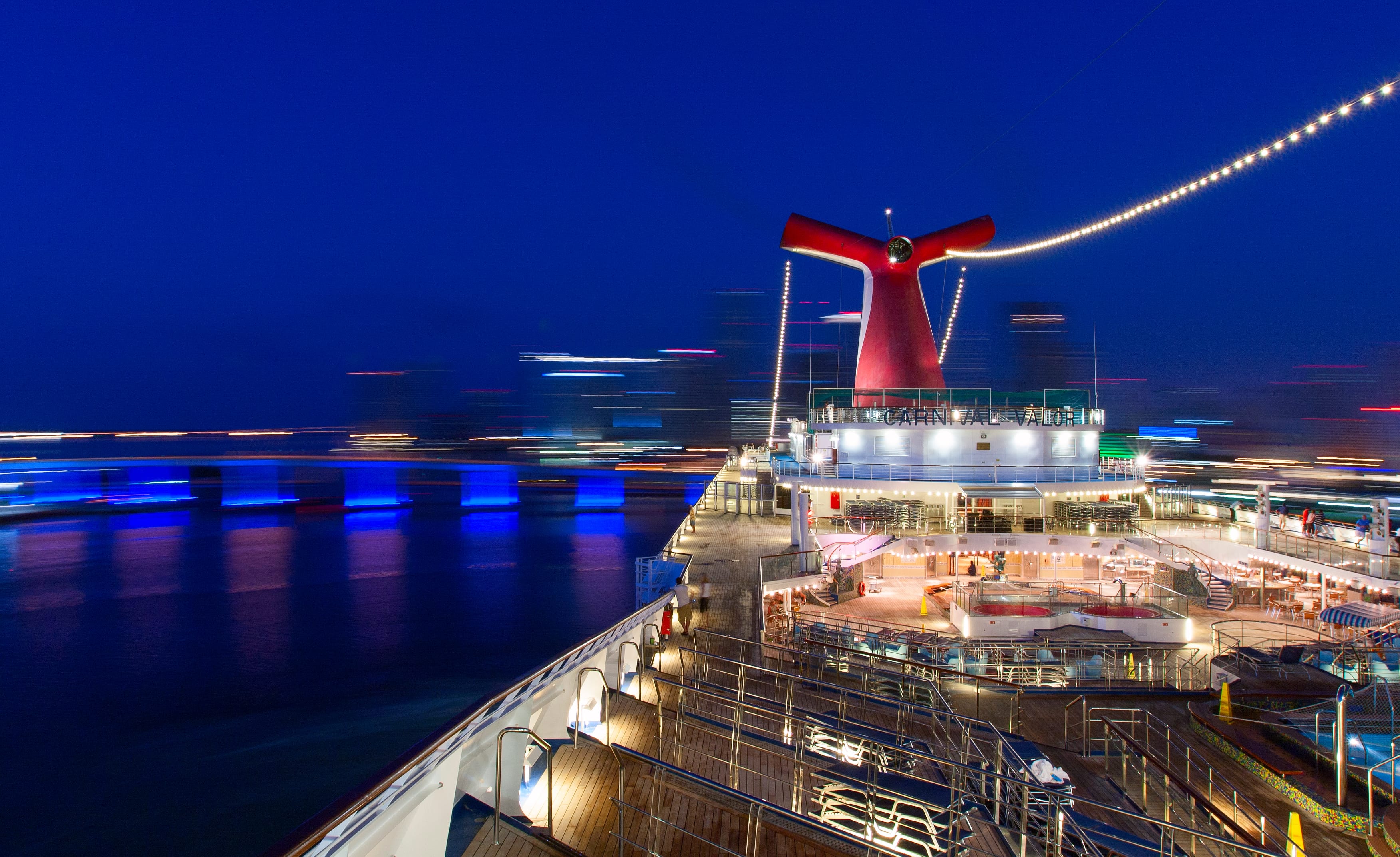 The Carnival Valor cruise ship sails through the night. Carnival's crew payments are provided by Brightwell's payroll solution, Navigator.