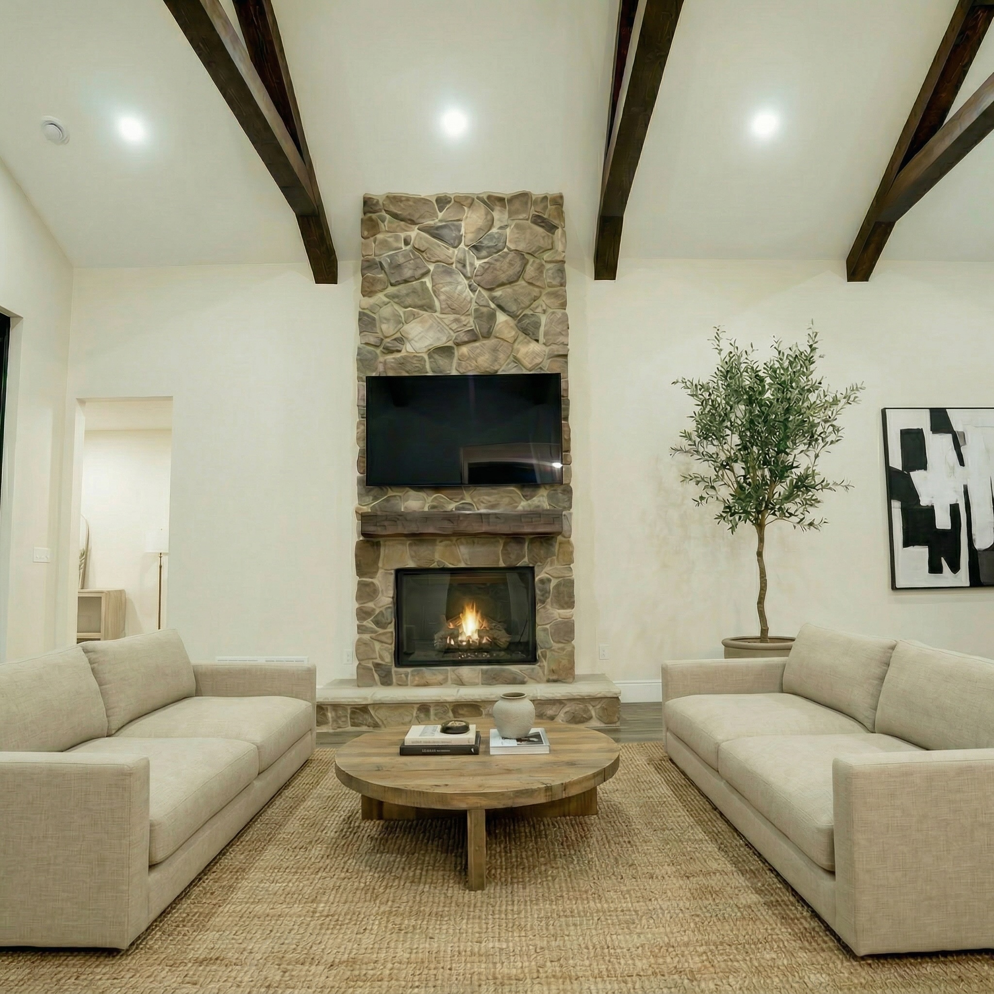 Veracious Developments great room with stone fireplace and exposed timber beams