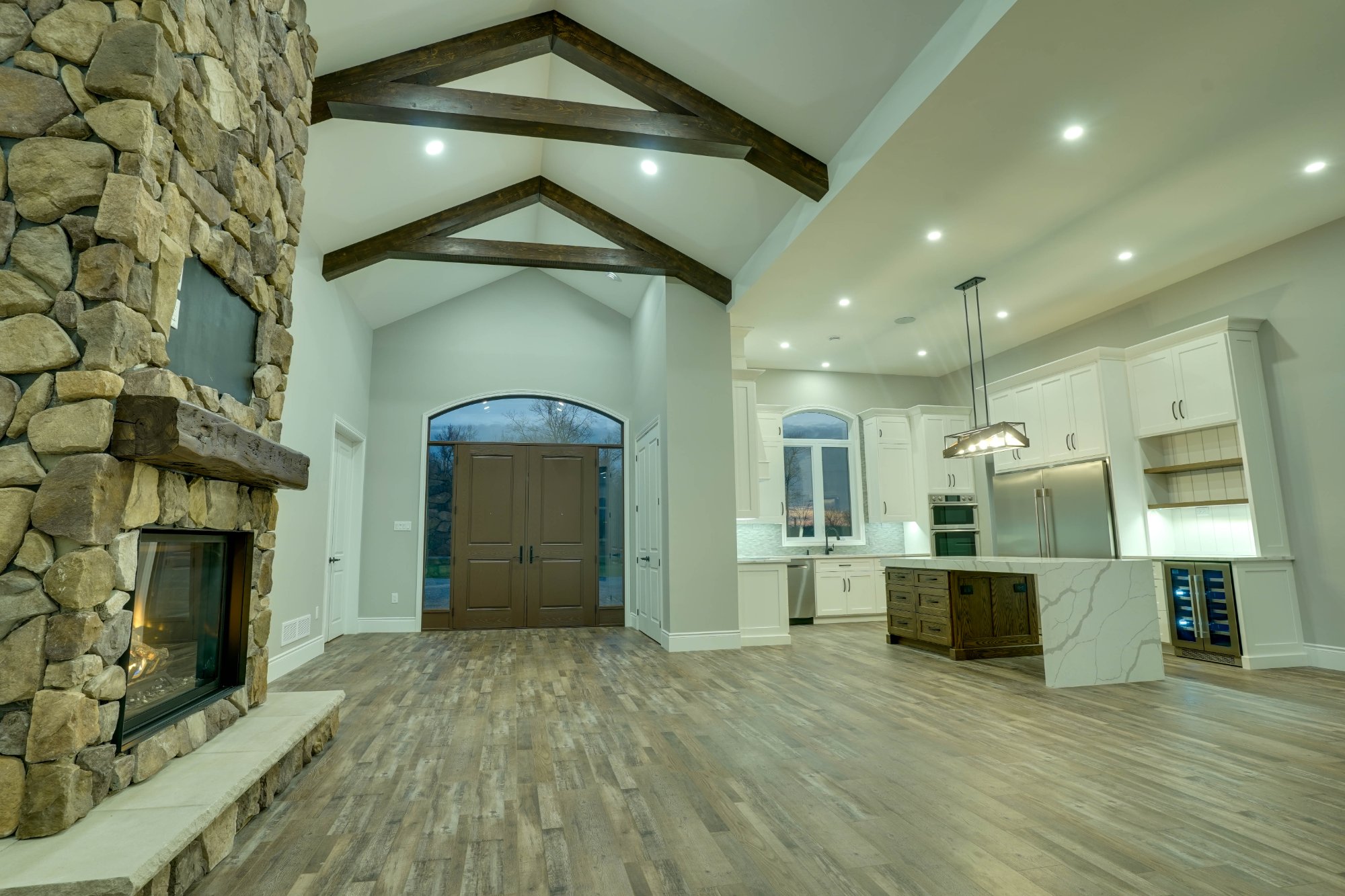 Veracious Developments great room with stone fireplace and exposed timber beams