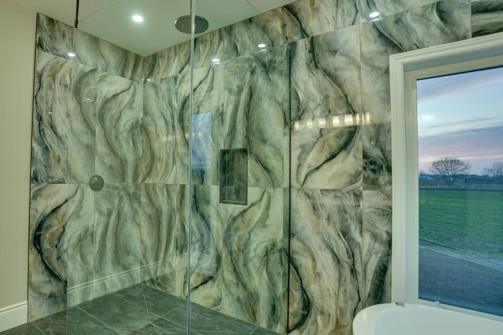 Primary ensuite soaker tub with sunset field view through windows