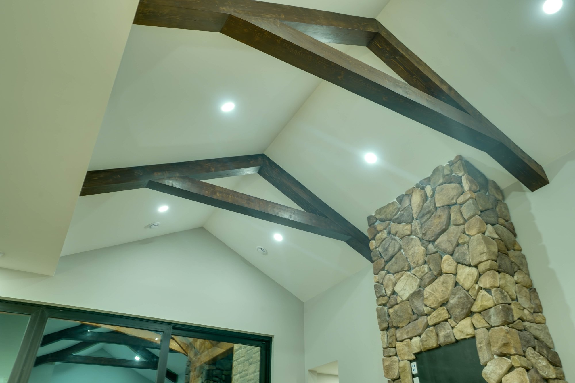 Veracious Developments great room with stone fireplace exposed beams and open concept layout