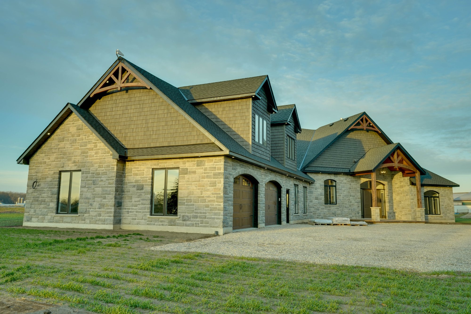 Veracious Developments wide exterior elevation with long driveway and open sky backdrop