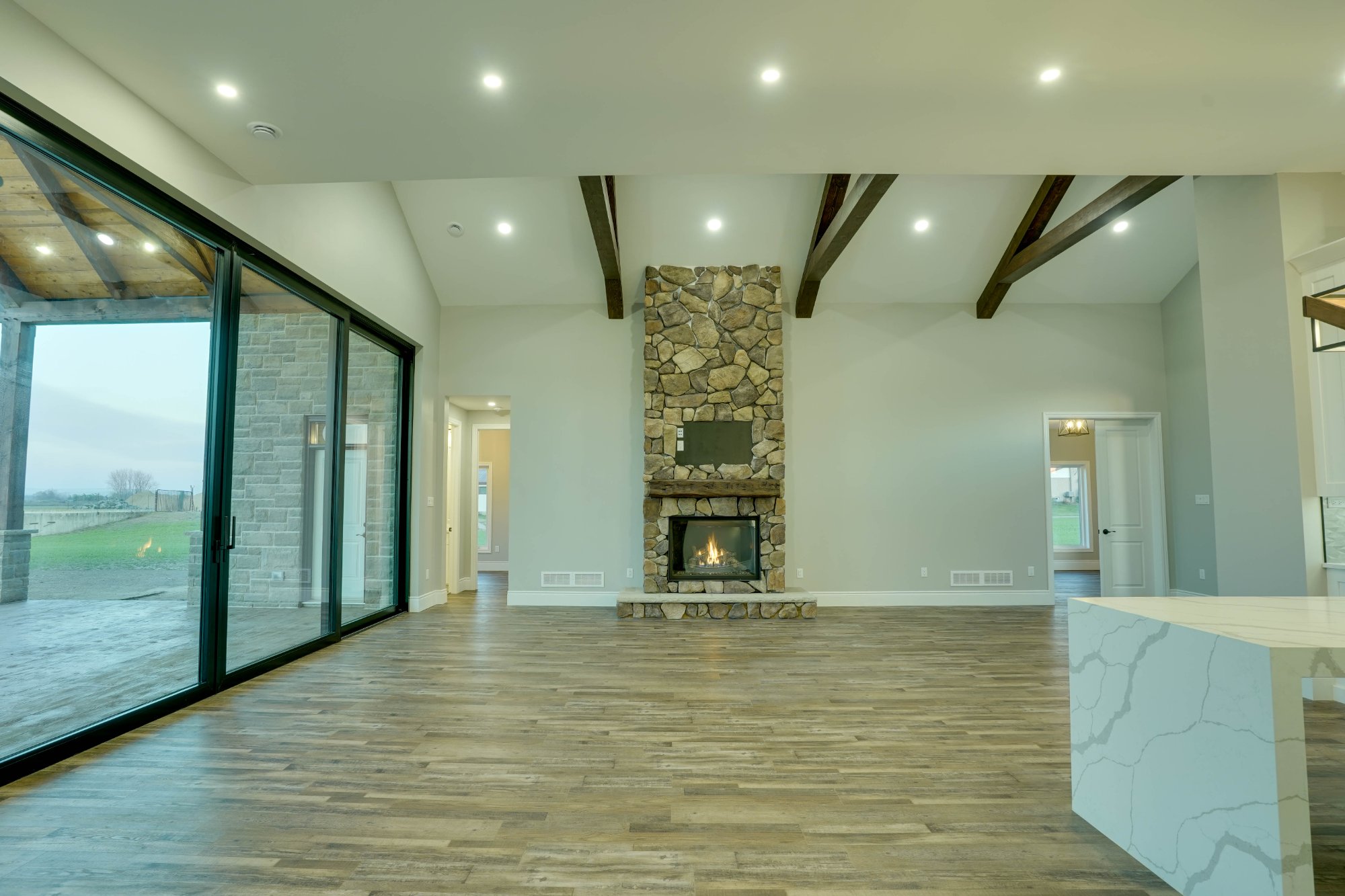 Veracious Developments great room with stone fireplace exposed beams and open concept layout