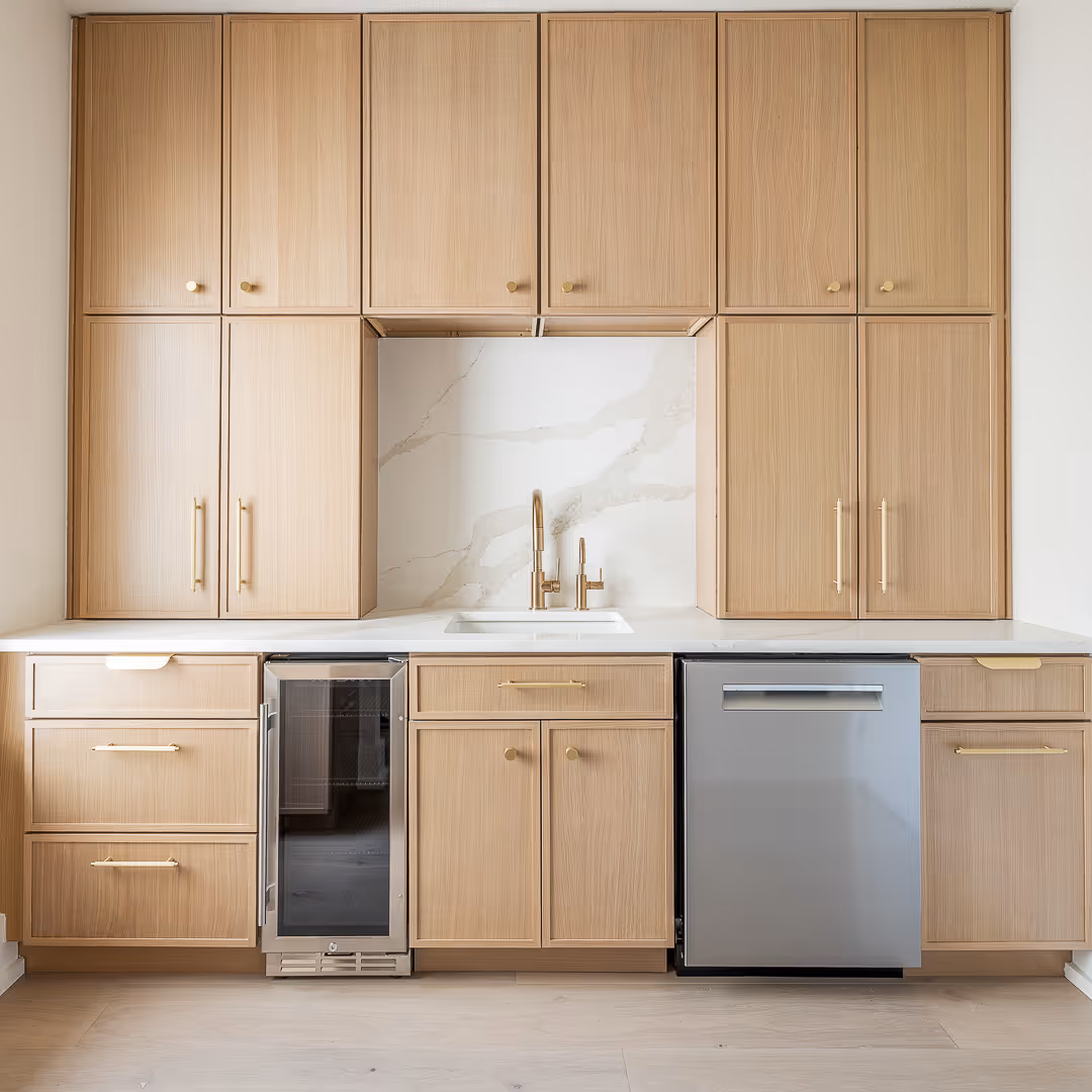 Modern kitchen with light wood cabinets, white countertop, dual gold faucets, wine fridge, and stainless steel dishwasher - Austin.