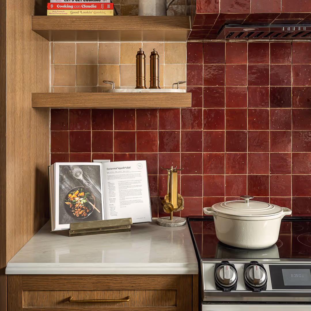 Modern kitchen stove against red tile backsplash.