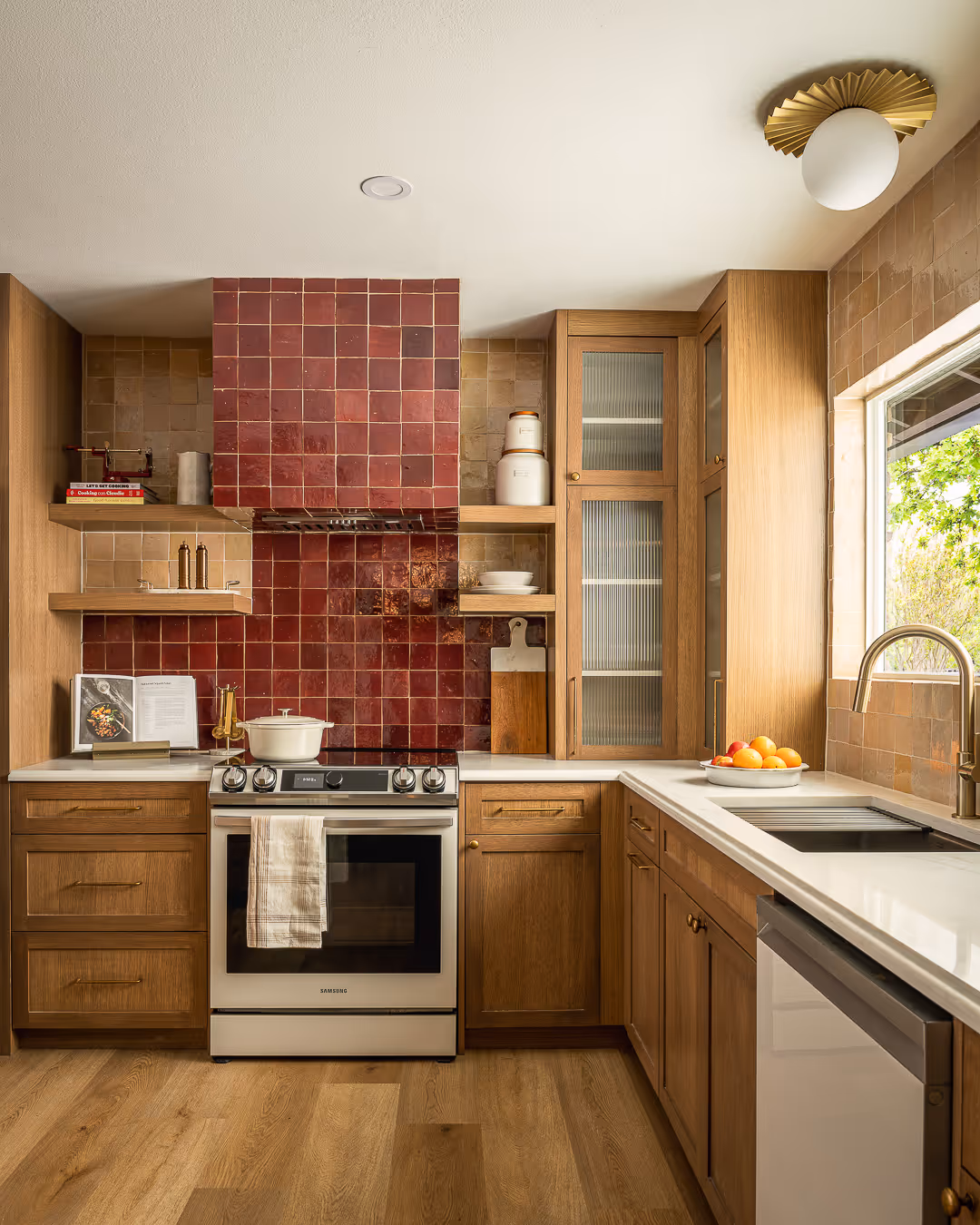 Modern kitchen with wooden cabinets, white countertops, red tiled backsplash, stainless steel stove, and a dish towel hanging from the oven handle.
