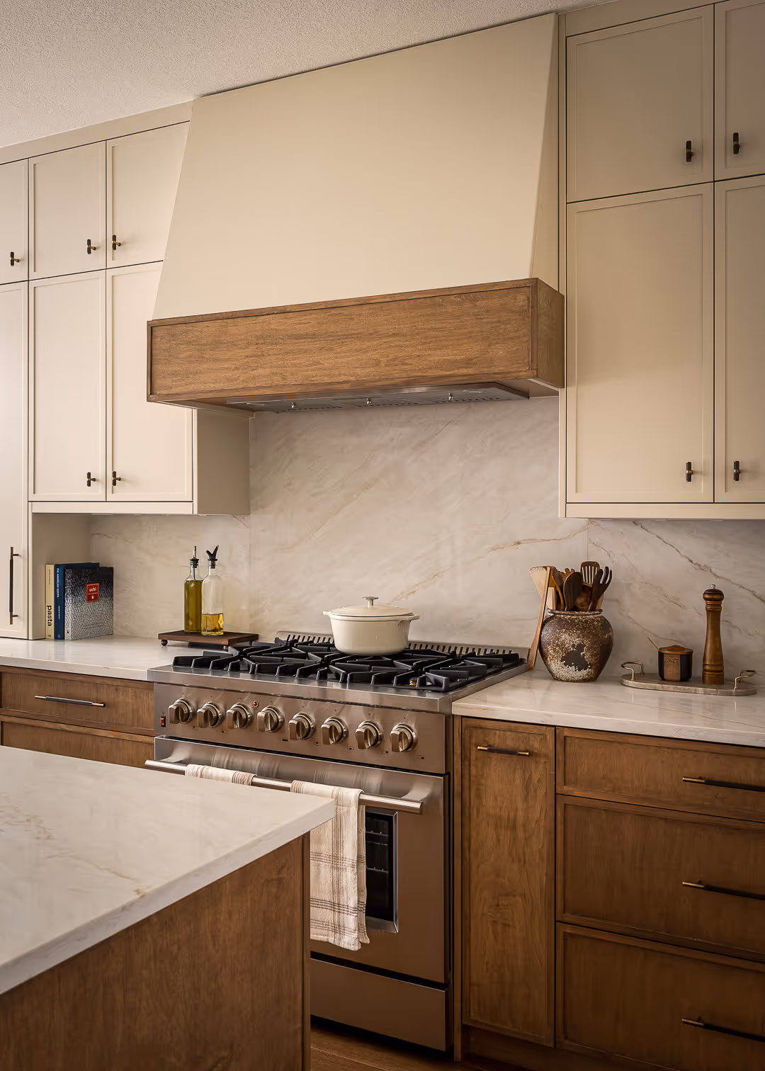 Modern kitchen with wood cabinets, light tile backsplash, white countertops, a window above the sink showing green trees outside, and stainless steel appliances.