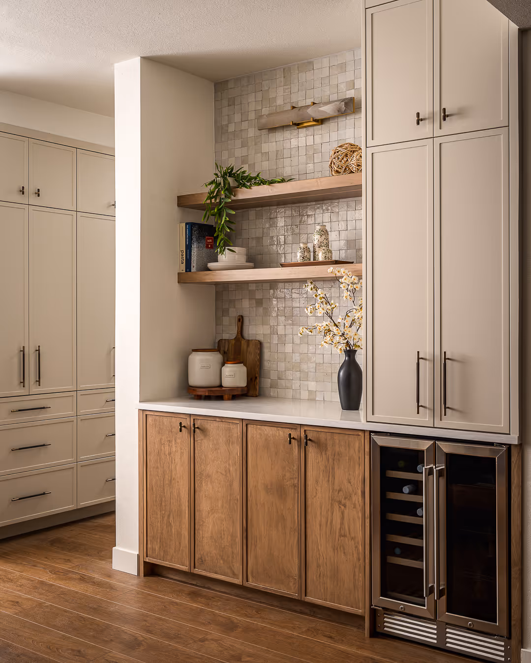 Modern kitchen with wood cabinets, light tile backsplash, white countertops, a window above the sink showing green trees outside, and stainless steel appliances.