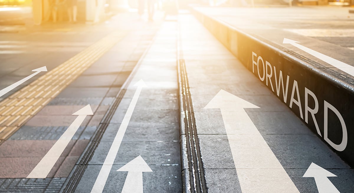 Arrows painted on stone steps and pavement pointing forward toward a bright light with the word FORWARD on the step edge.