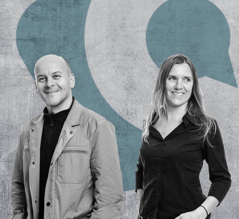 Smiling man and woman standing in front of a textured wall with large blue quotation marks.