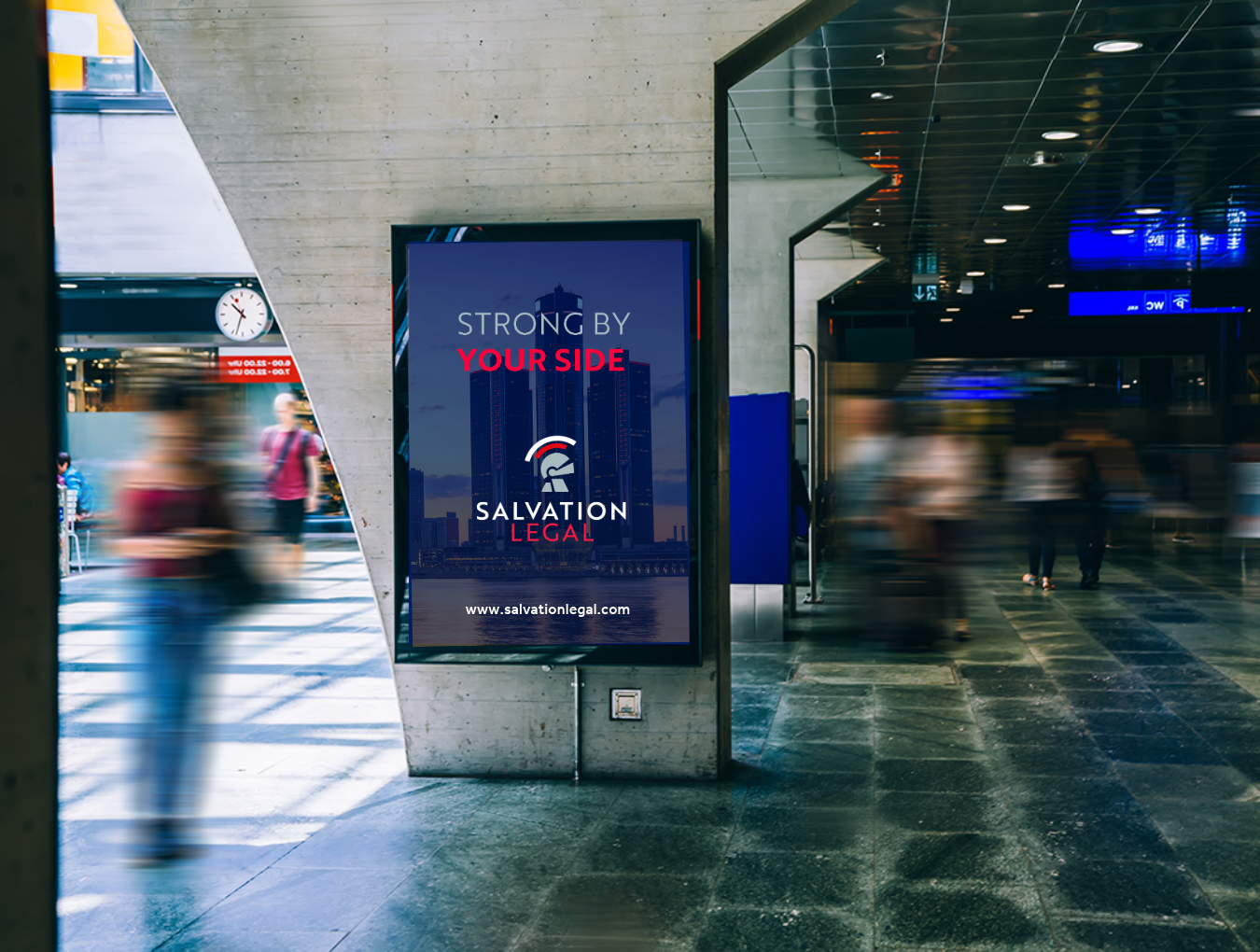 Digital advertisement for Salvation Legal with text 'Strong by Your Side' displayed on a concrete pillar in a busy transit station.