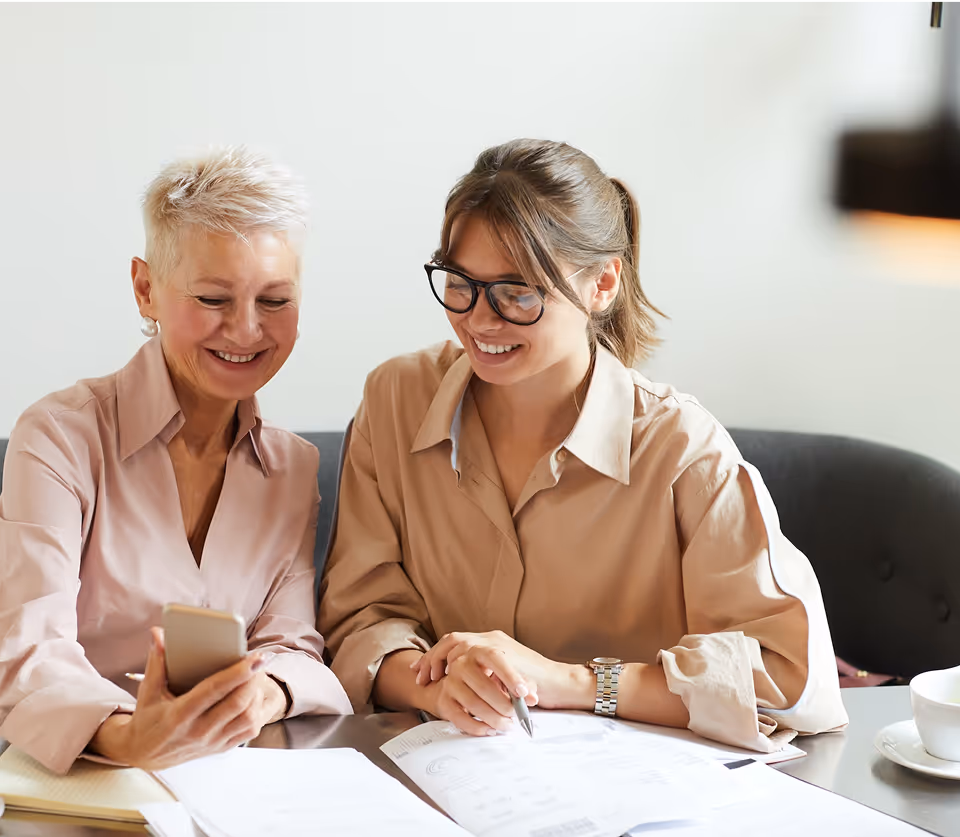 A couple of women sitting at a table next to each other.