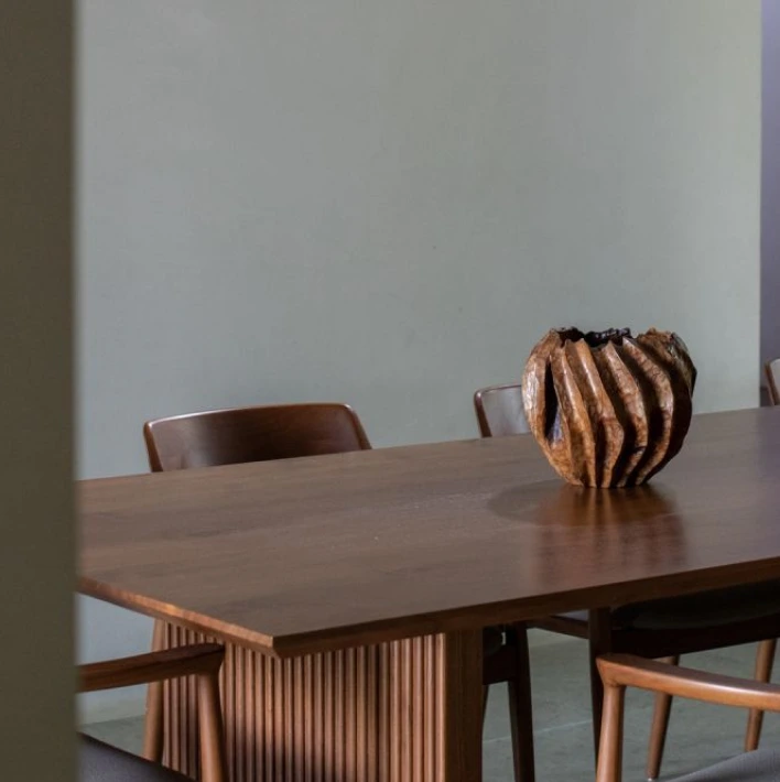 Wooden dining table and chairs with a sculptural object placed at the center.