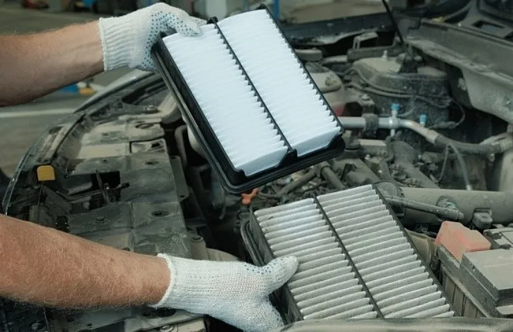 Gloved hands holding clean air filter.