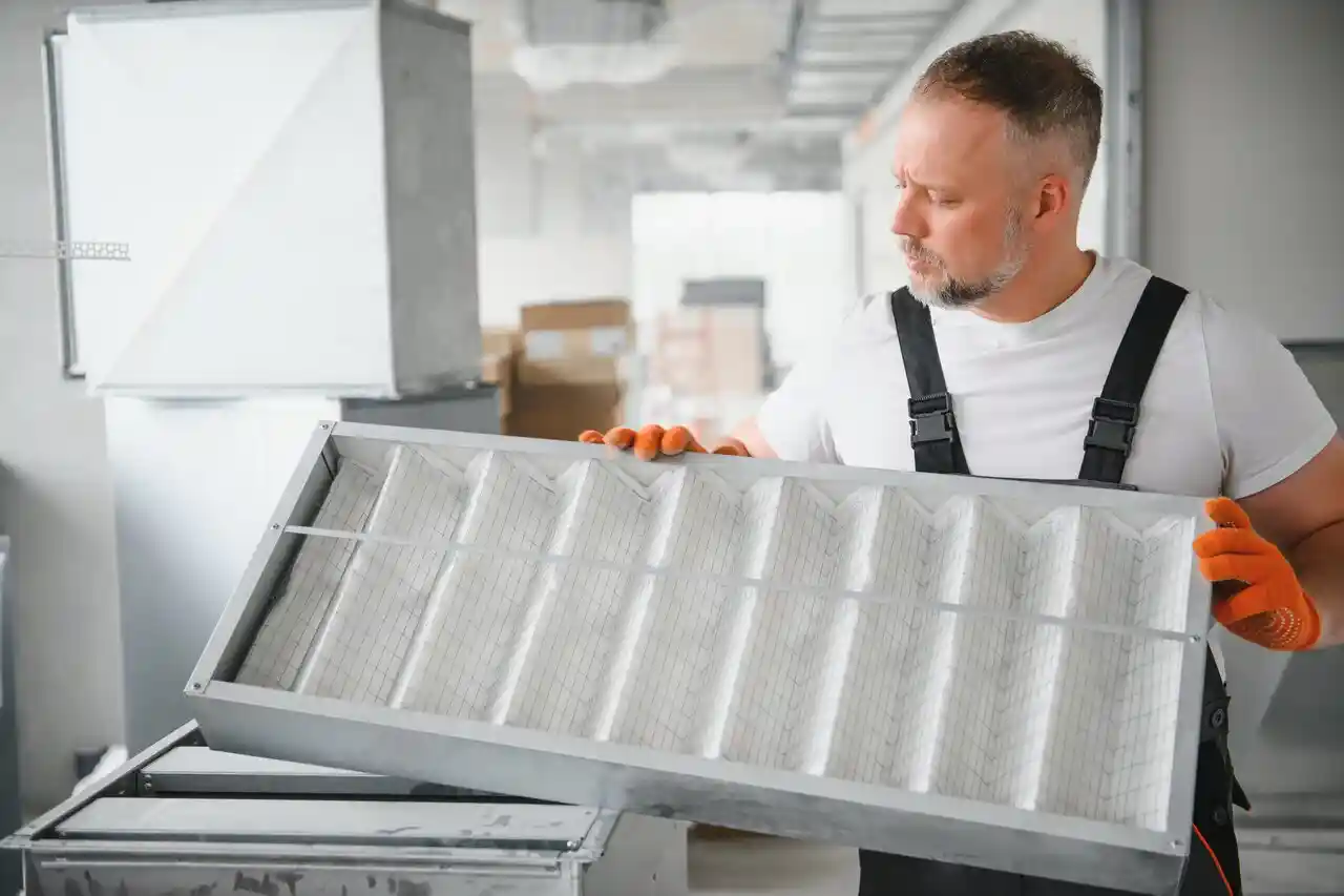 Technician holds large white air filter.