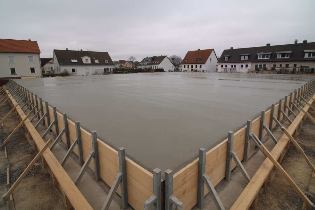 Frisch betoniertes Fundament mit sichtbarer Bewehrung auf einer Wohnbaustelle