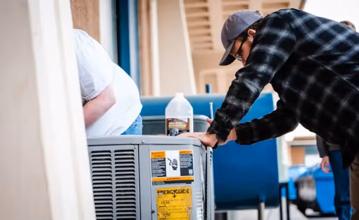 A man inspecting a AC unit installed outside a home