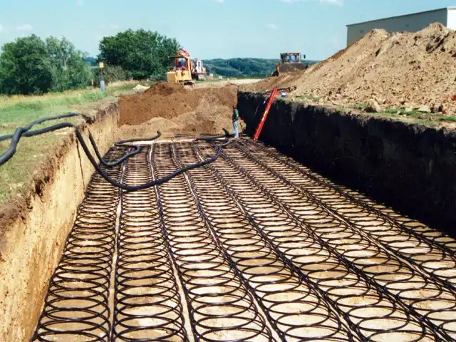 Installation of a horizontal ground loop heat exchanger, with coiled piping laid in an open trench