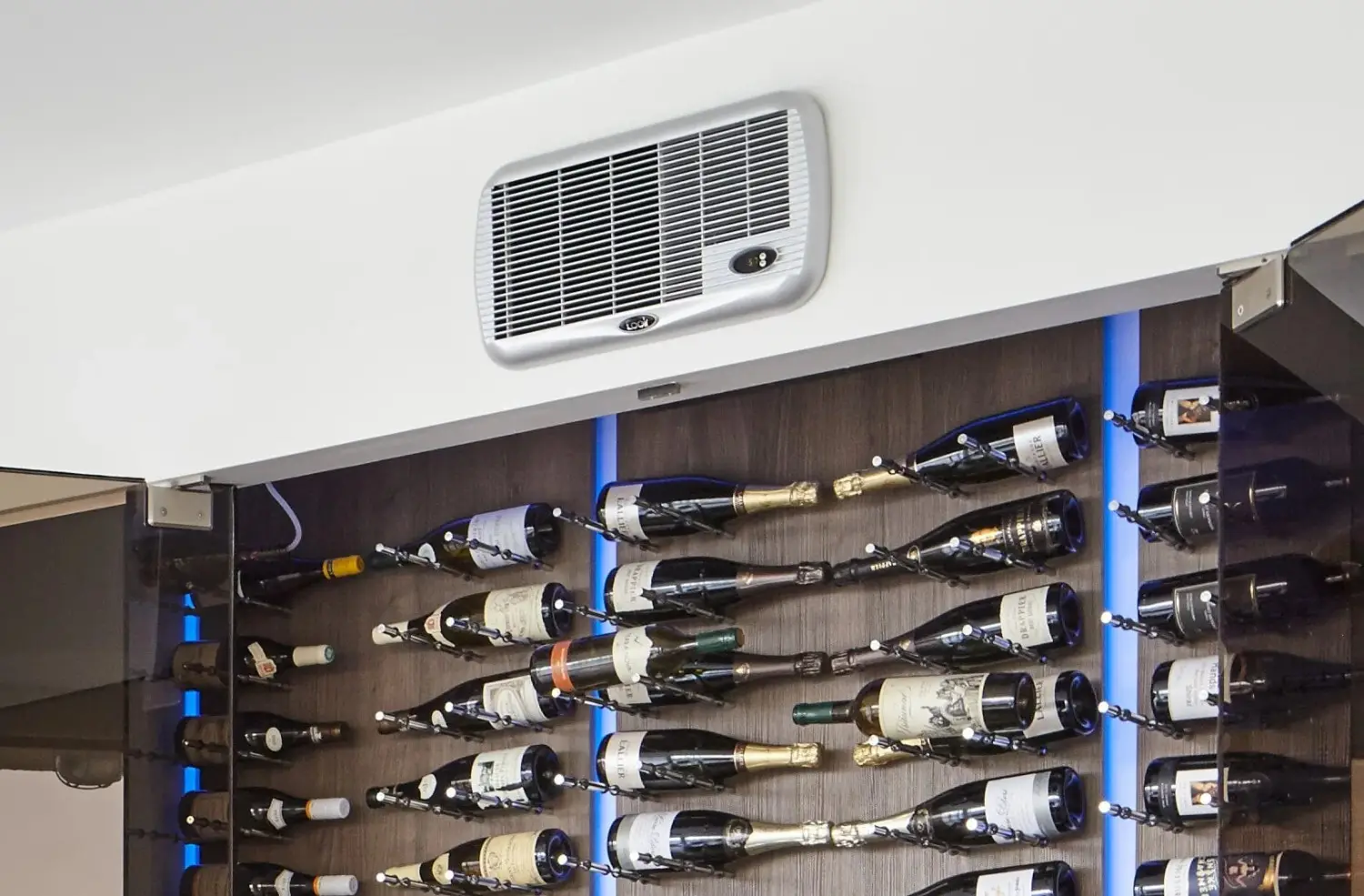 A silver wine cellar cooling unit mounted on a wall above a modern wine rack with blue accent lighting.