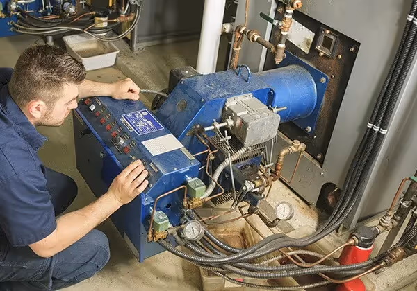 Technician adjusting controls on commercial boiler.