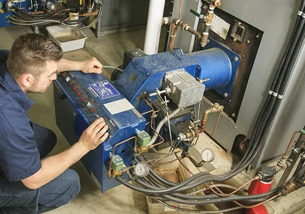 Technician adjusting controls on commercial boiler.
