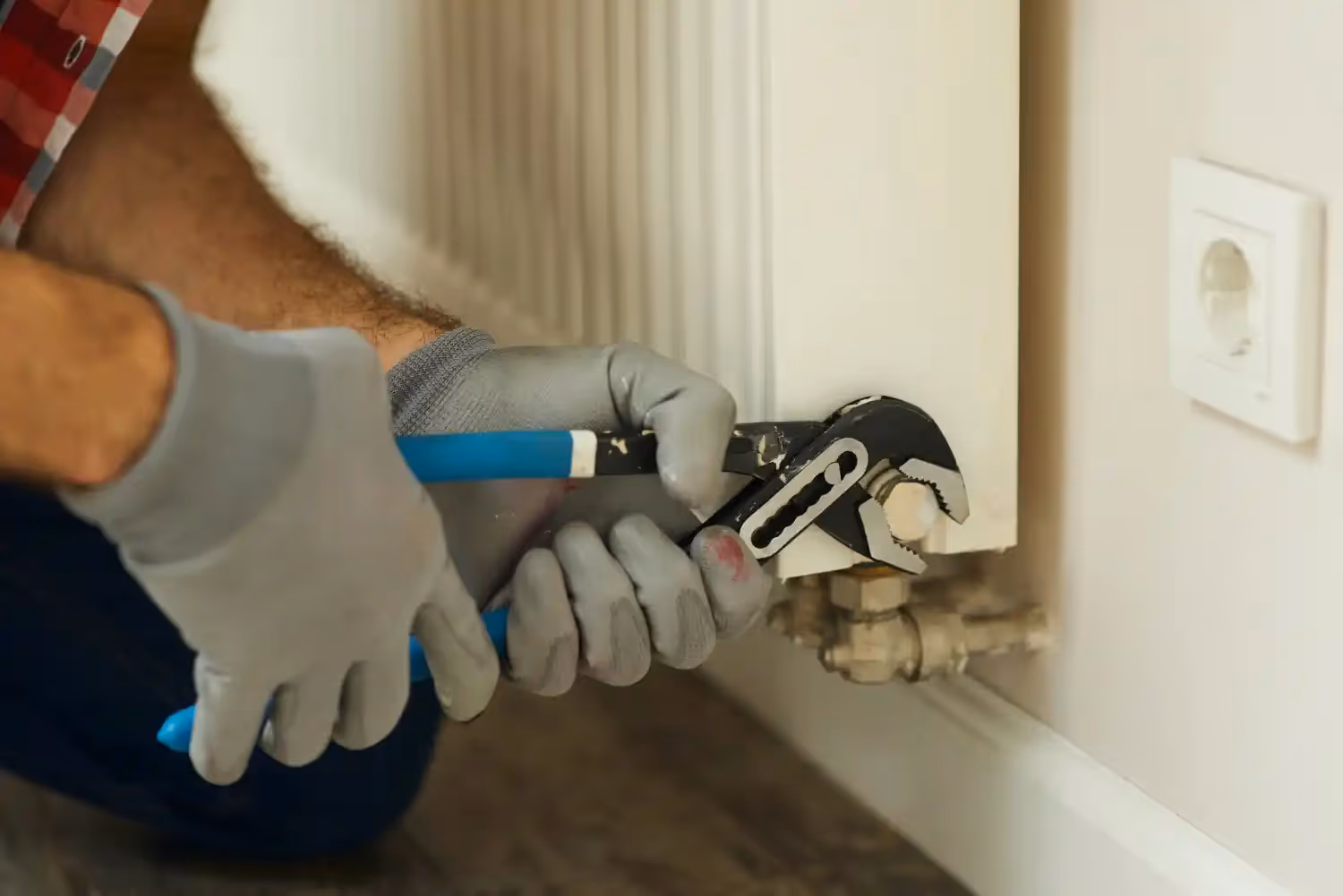 Technician using pliers on radiator valve.