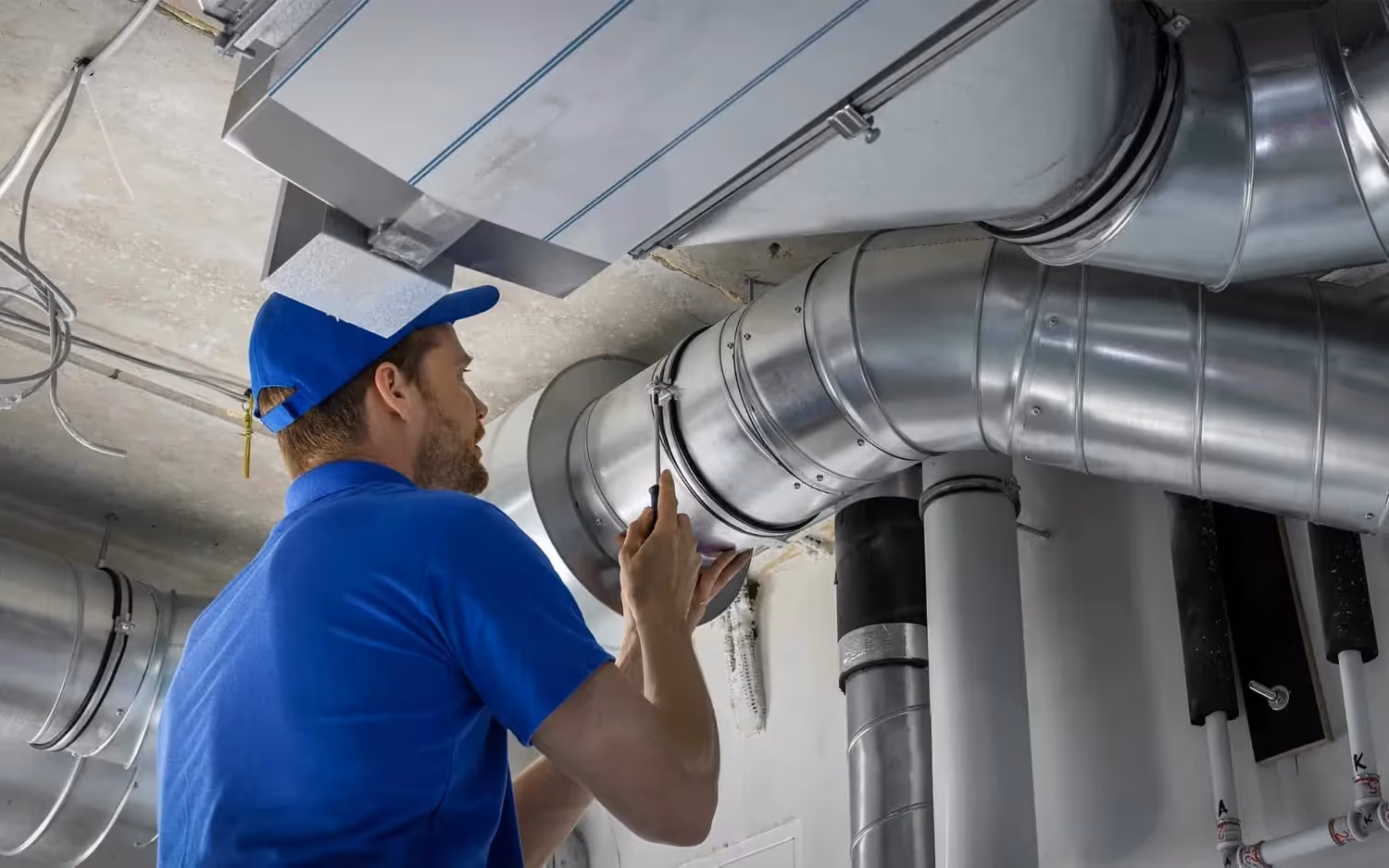 Technician installing rigid metal HVAC ducting.