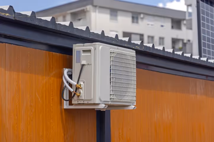 An outdoor air conditioner unit mounted on the side of a building.