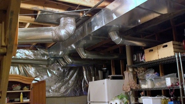 The image shows a basement with exposed metal ductwork on the ceiling. 