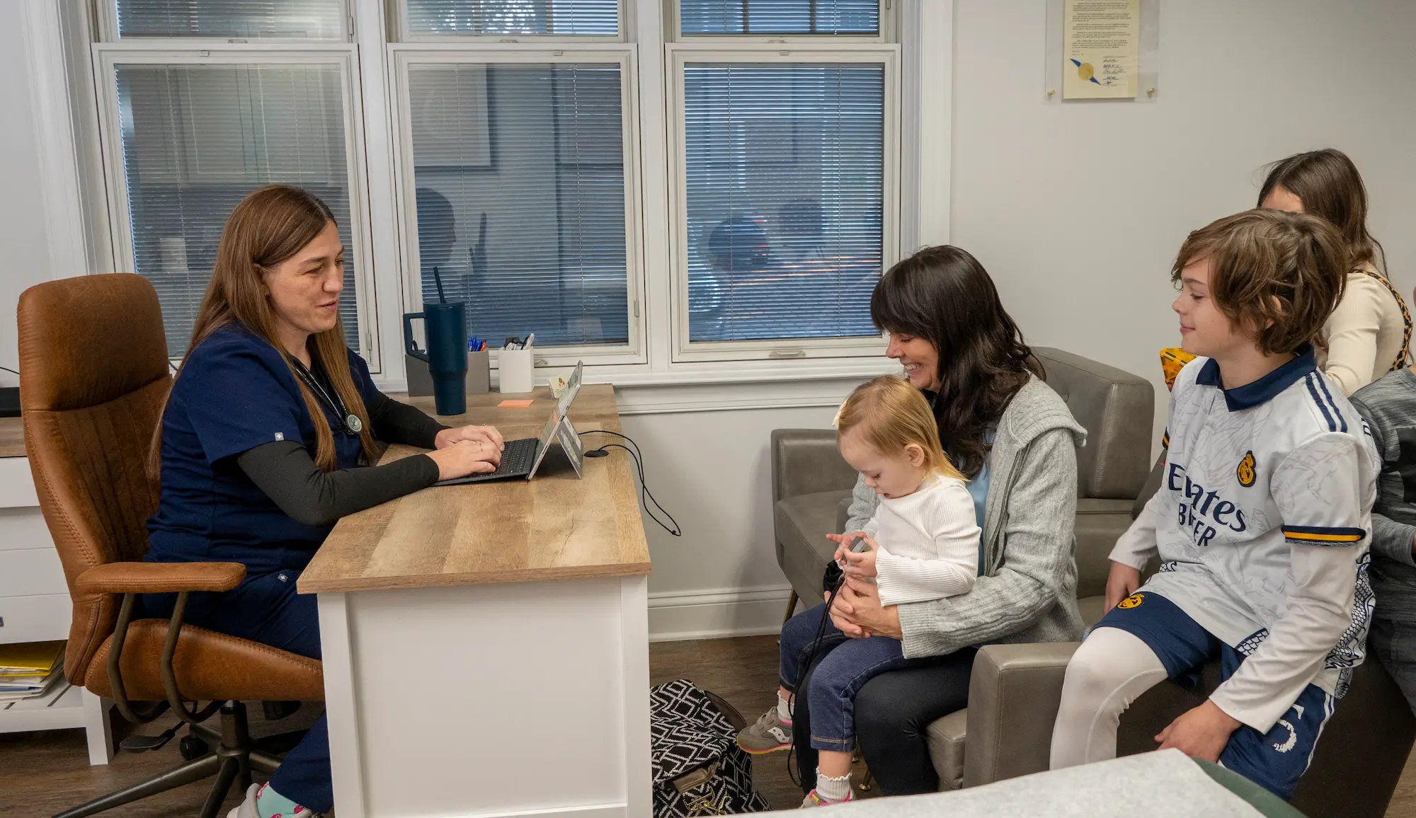 a photo of the provider meeting with a family of a mother and three children