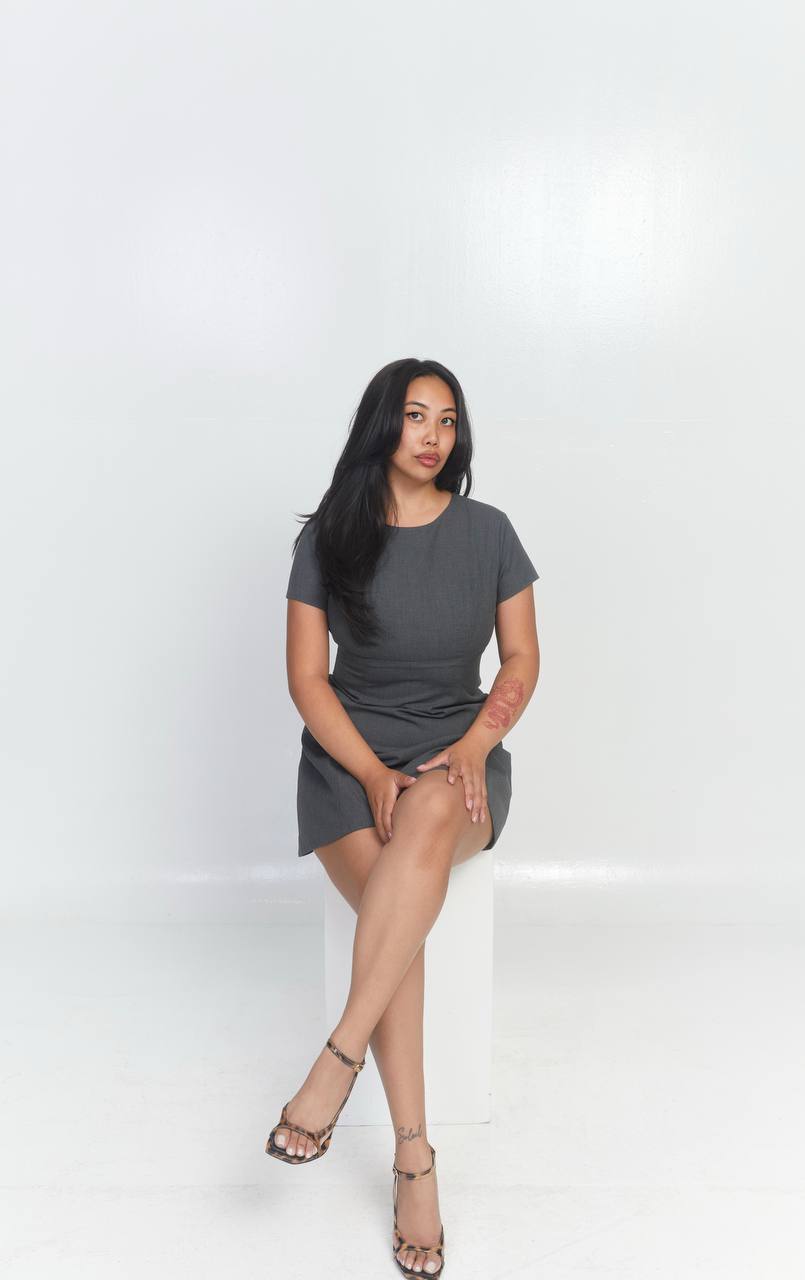 a lady with blonde curly hair using a computer in a office, we can see her coworkers in the background