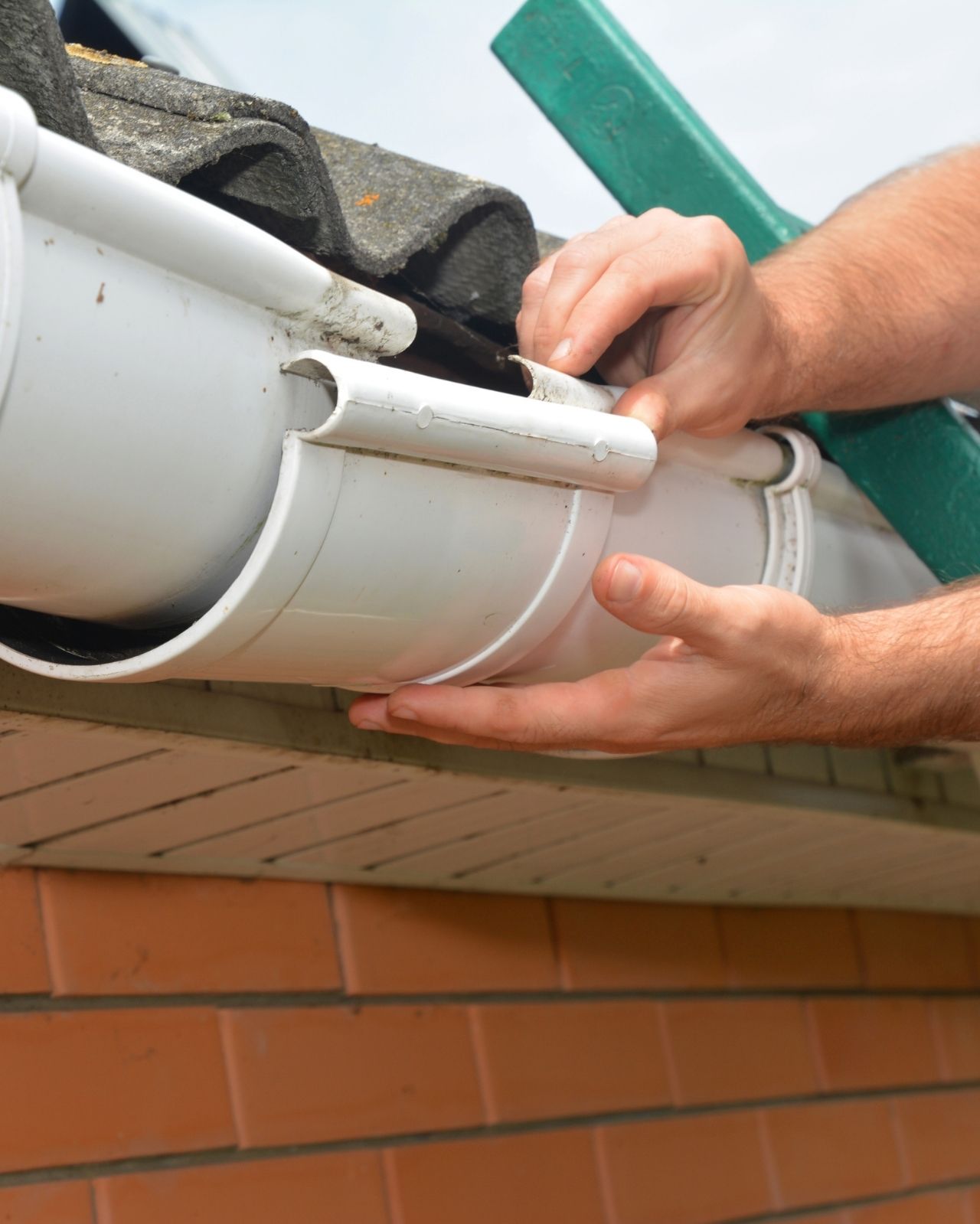 Gutter pipeline installation. Roofer contractor installing and repair rain gutter. Guttering repair with contractor hands
