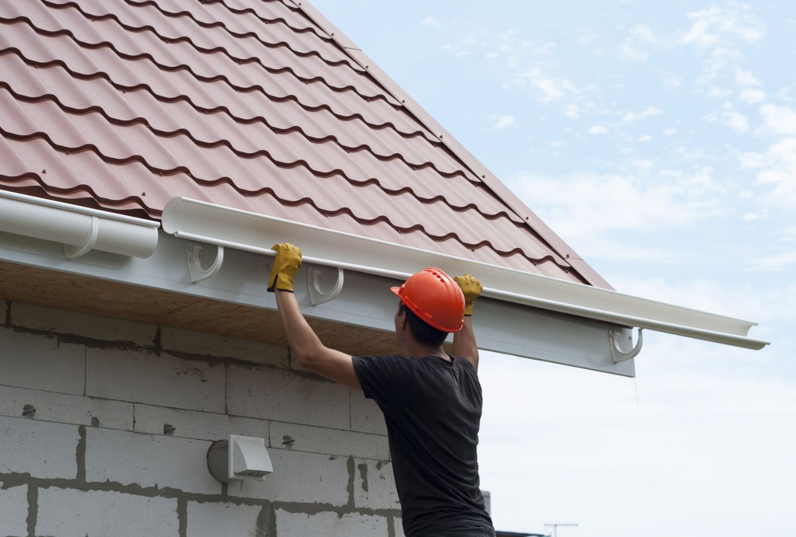 worker installing the gutter system on the roof