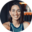 Lächelnde Frau in Sportkleidung, kurzes dunkles Haar, in einem Fitnessstudio.