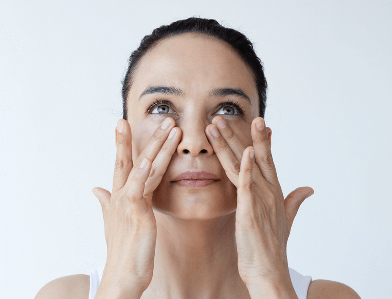 Frau massiert sanft Gesicht, Pflege der Augenpartie, Hautpflege-Routine.