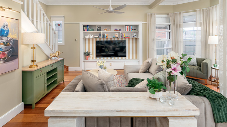 A bright, clean living room with minimal clutter and a bookshelf.