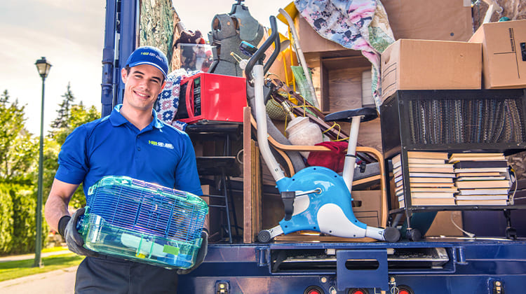 A Truck Team member standing at the back of a truck with all the junk inside it.