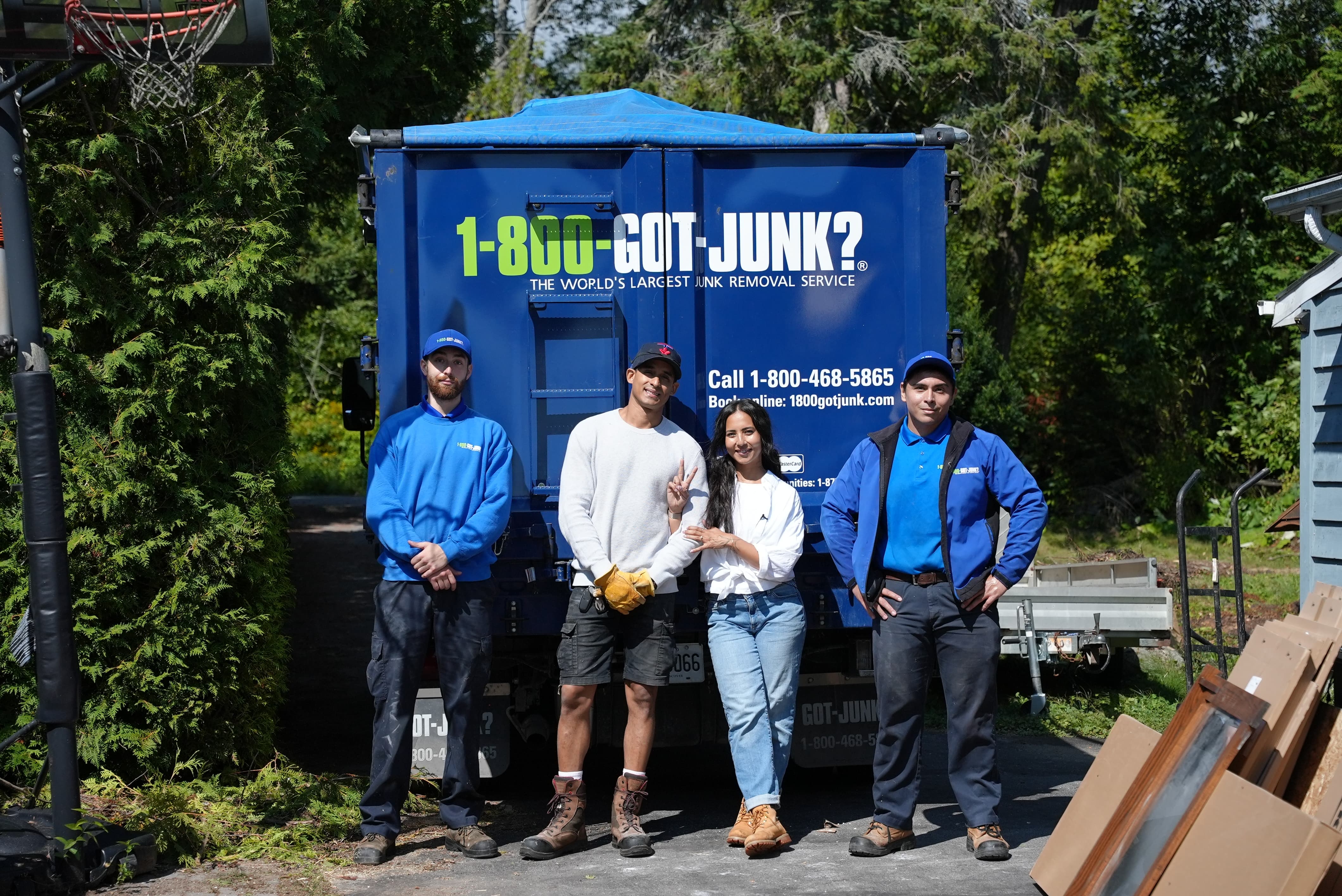 Une femme et deux équipiers de 1-800-GOT-JUNK? qui sourient devant un camion.