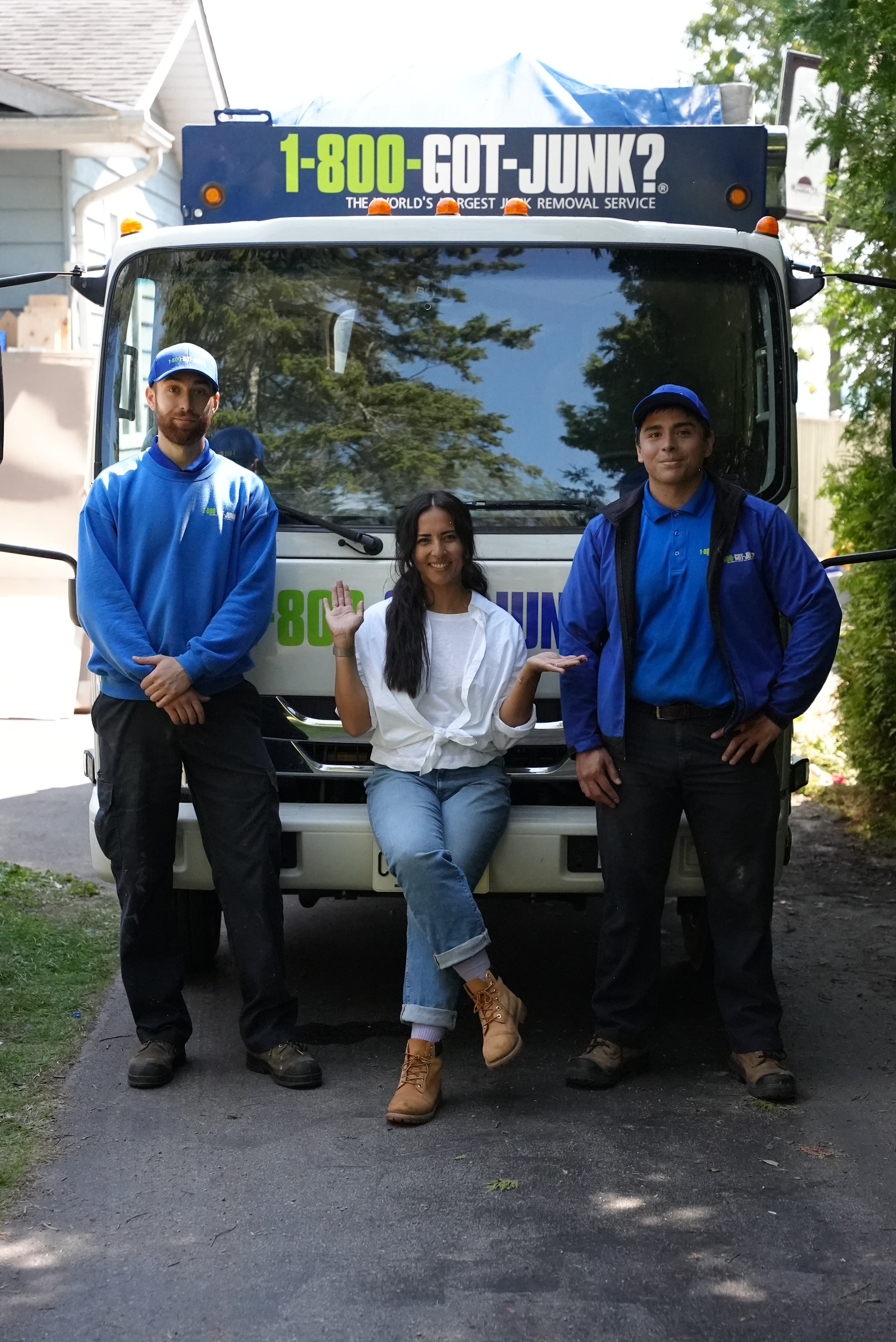 Une femme et deux équipiers de 1-800-GOT-JUNK? qui sourient devant un camion.