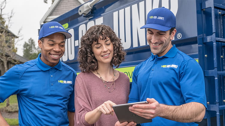 Two 1-800-GOT-JUNK? Truck Team Members and a customer going over an estimate.