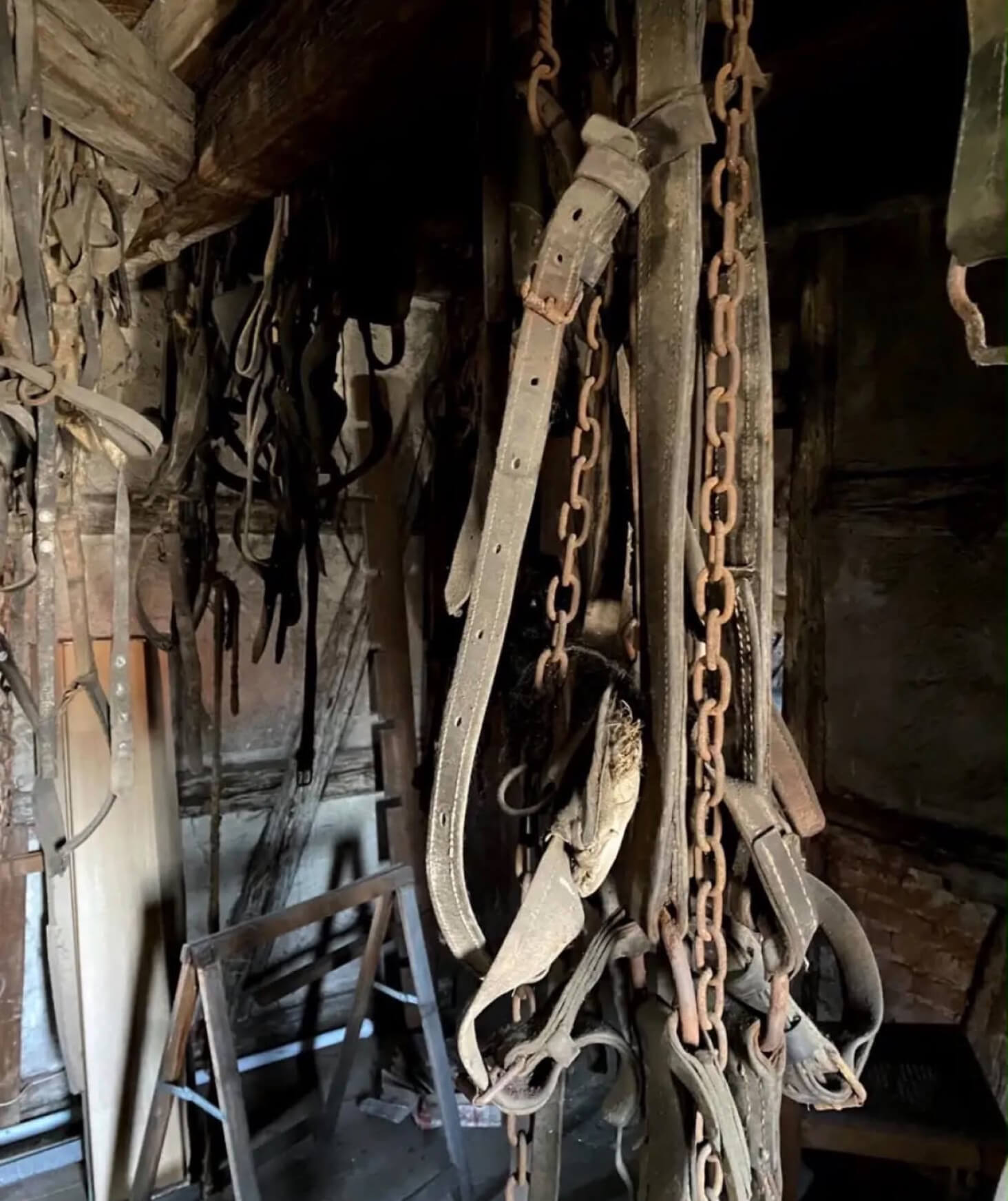 A room of chainsaws, belts, and tools hanging from the ceiling.