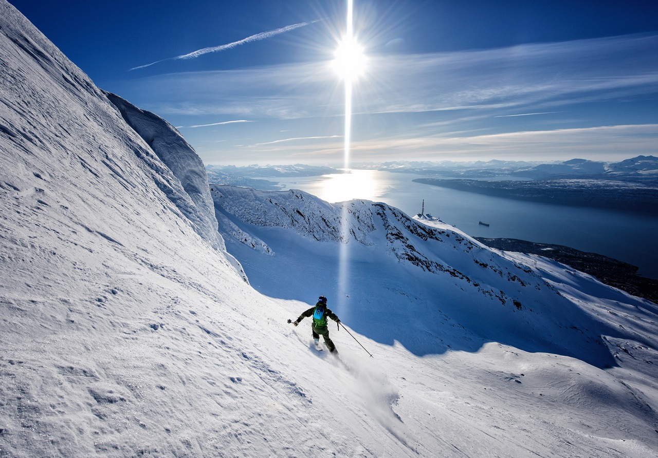 Person skiing down a mountain in sunlight
