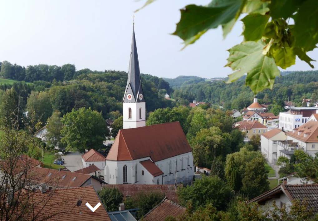 Blick über die idyllische Kleinstadt Reischach mit Kirche und grüner Hügellandschaft