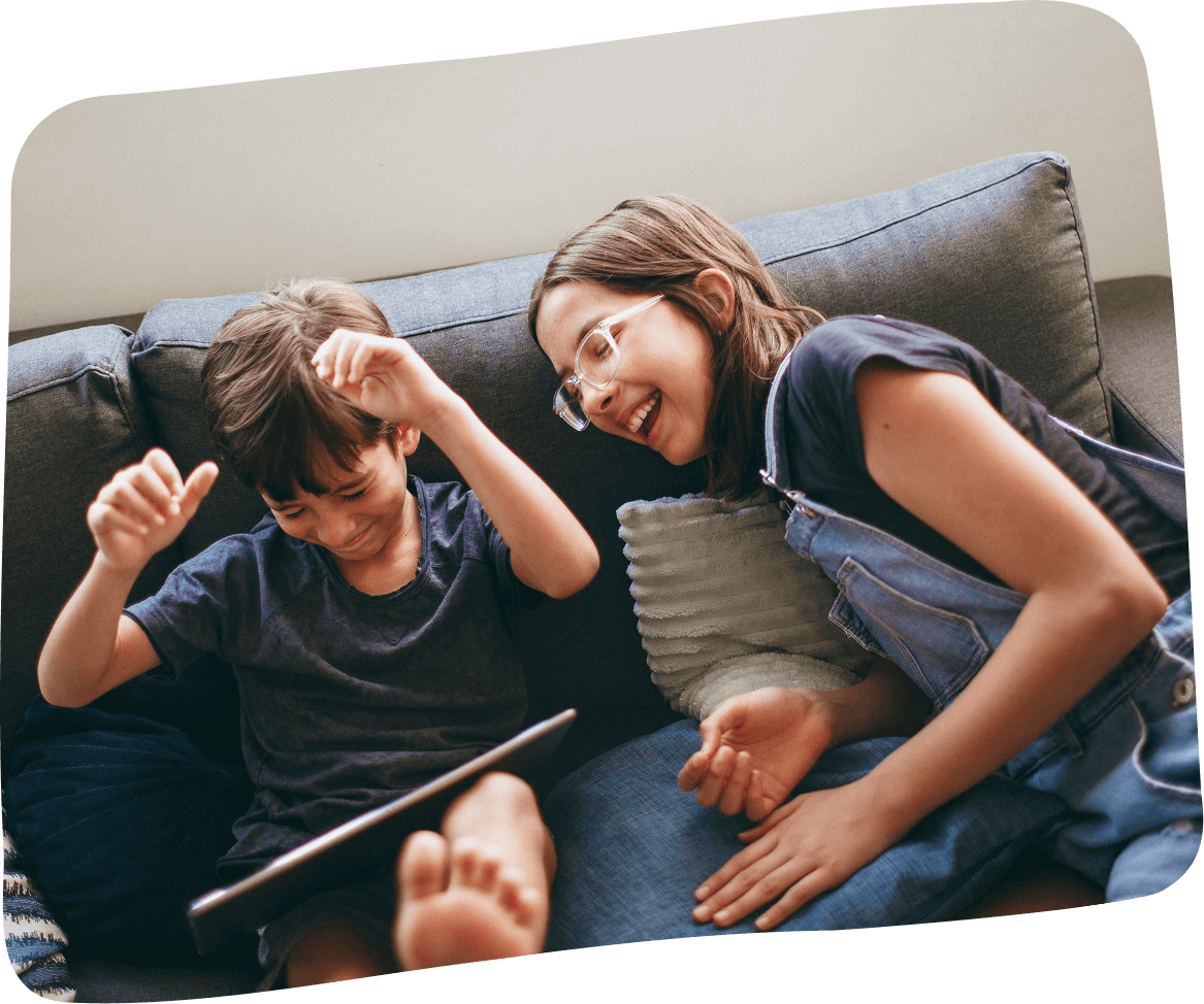 A boy and a girl sitting on a couch, smiling and playing Elody game.