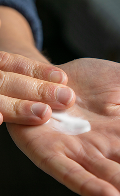 Hand met een witte crème of lotion die op de palm wordt aangebracht.