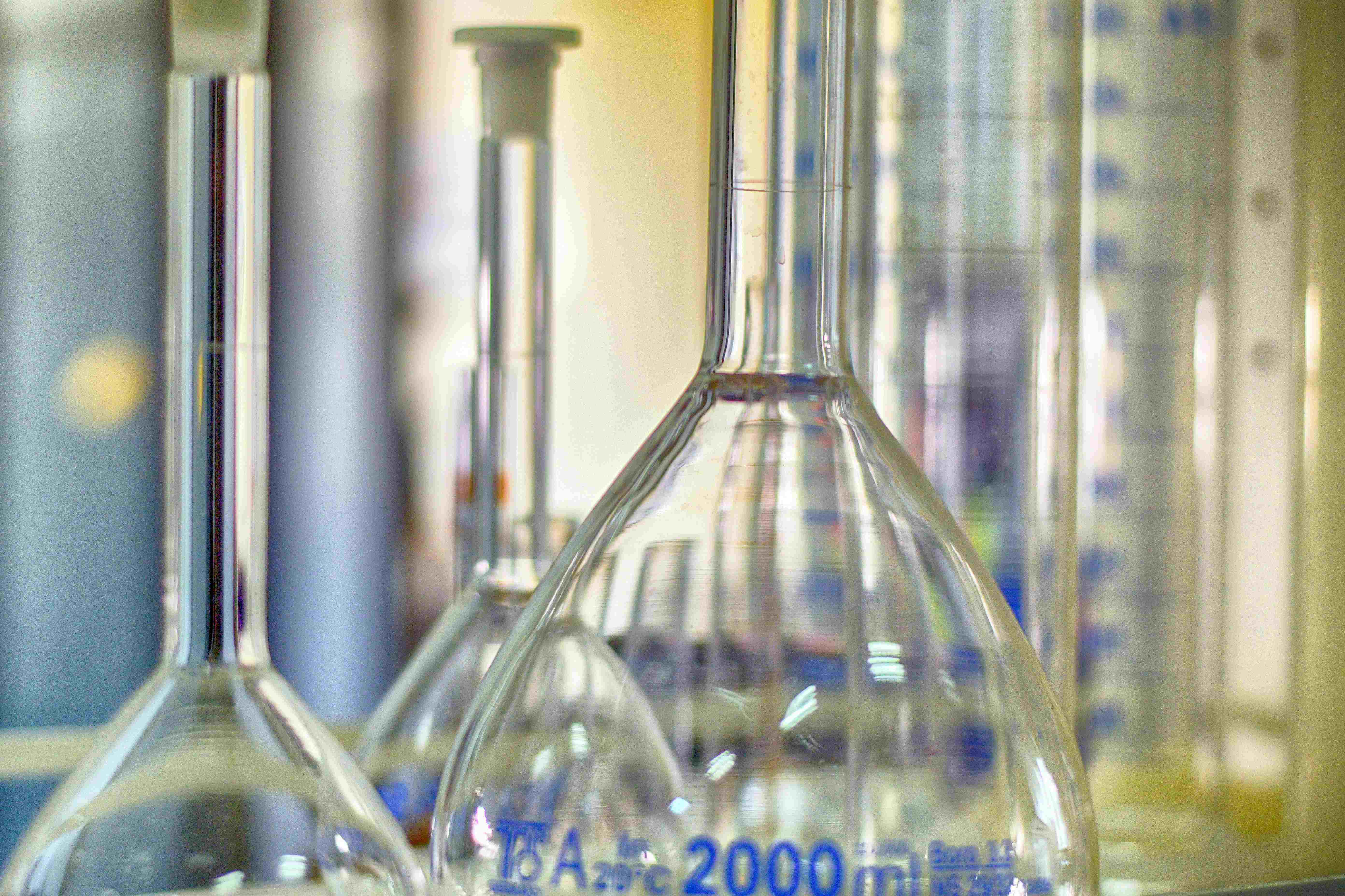 Dichtbij van glazen laboratoriumflessen en maatcilinders met meetmarkeringen.