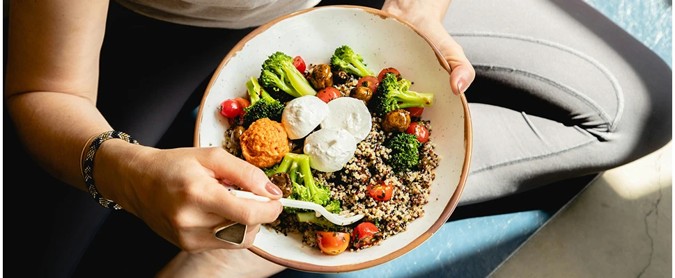 Pratiquant de yoga qui mange une assiette de salade.