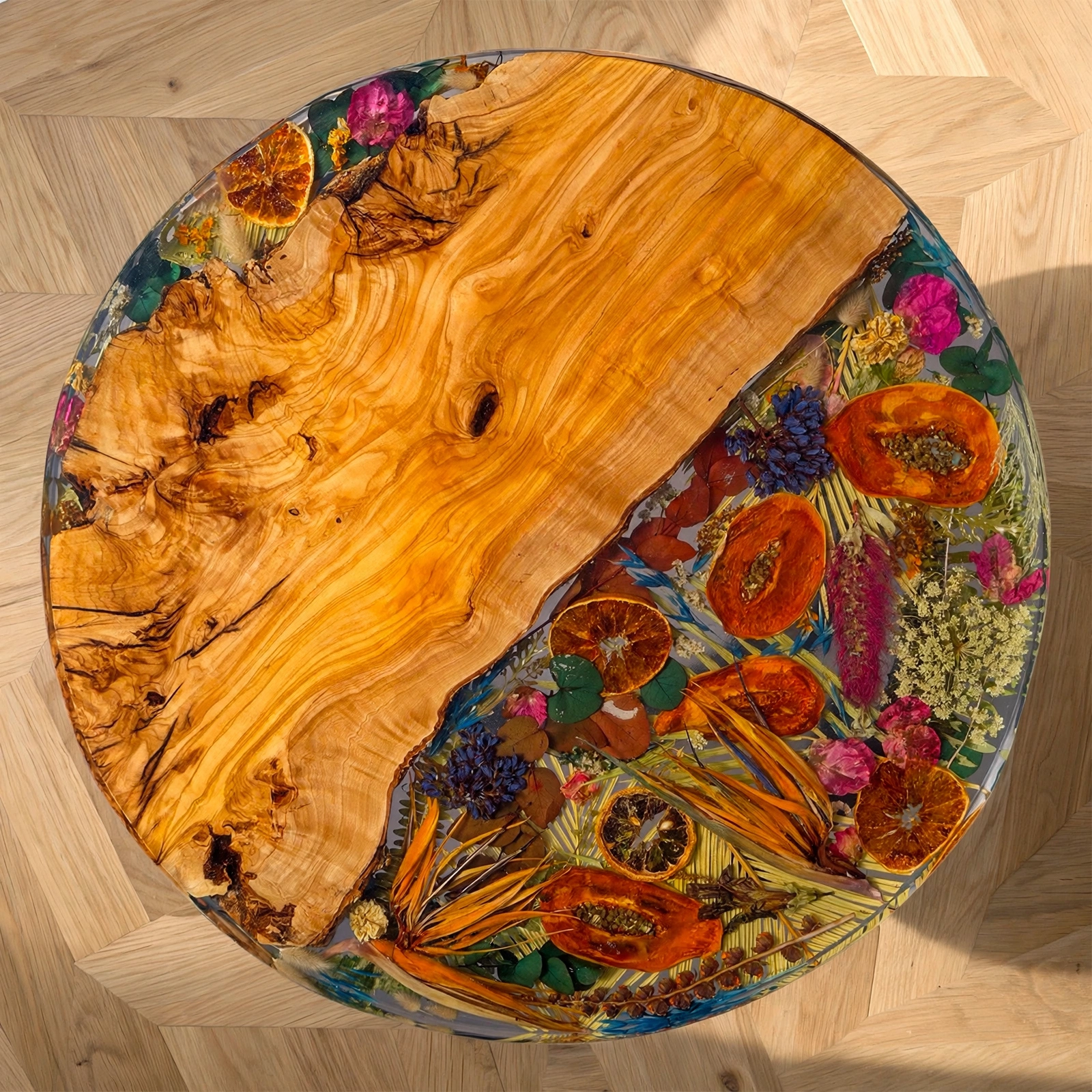Vista cenital mesa centro 60cm olivo y resina epoxi con frutas papaya naranja y flores preservadas sobre parquet claro - Aluna Crafted Mallorca
