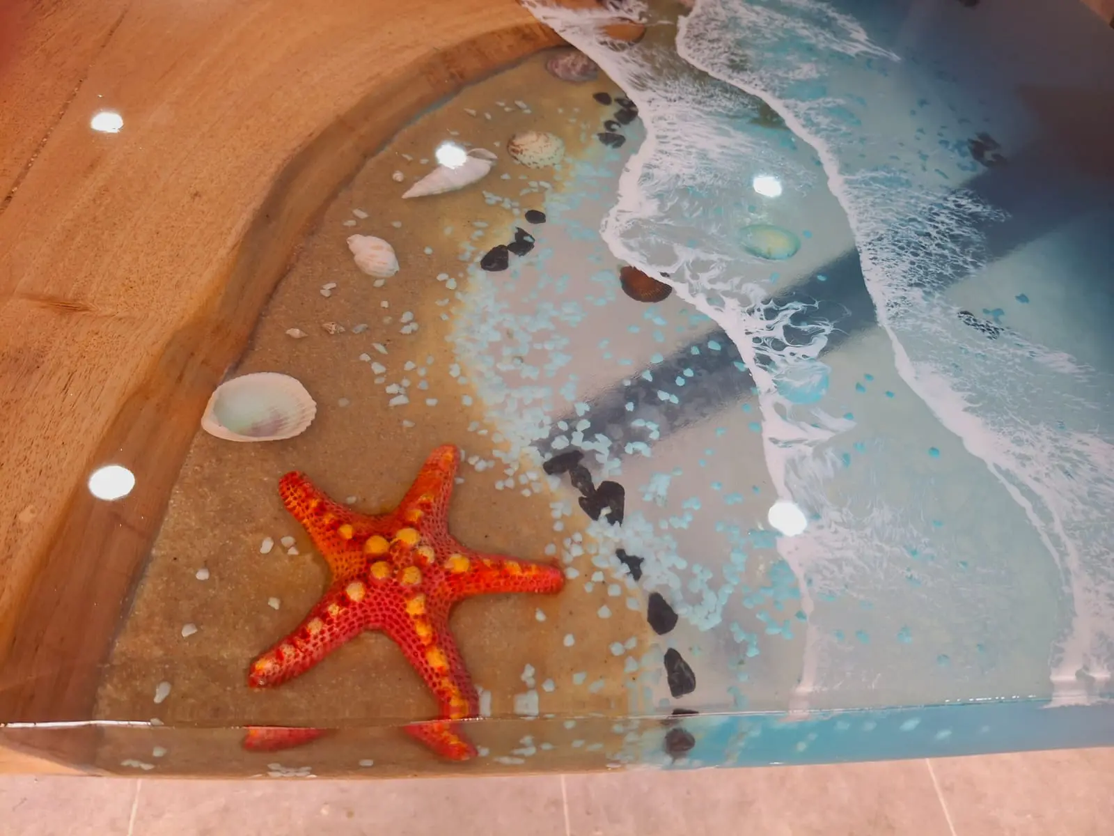 Detalle de mesa de resina epoxi con estrella de mar roja, conchas y efecto oceano - Aluna Crafted Mallorca